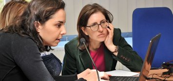 3 Frauen vor einem Rechner:  eine gibt etwas ein, eine andere konzentriert schaut zu.