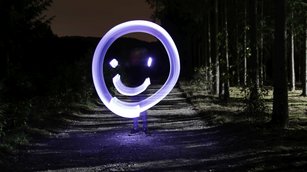Lightpainting-Foto: Mit Licht gemaltes Smiley in einer dunklen Umgebung