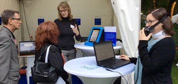 Susanne Böhmig am Stand der STIFTUNG barrierefrei kommunizieren! erklärt  Besuchern unterstützende Technologien